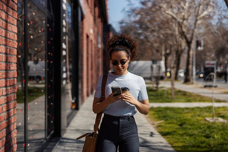 woman walking down the street using her phone
