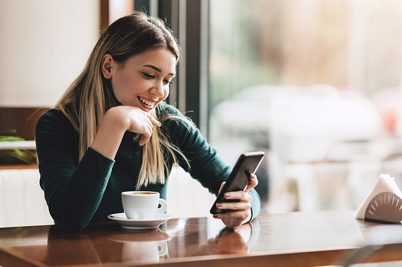 woman sitting in a coffee shop using her phone
