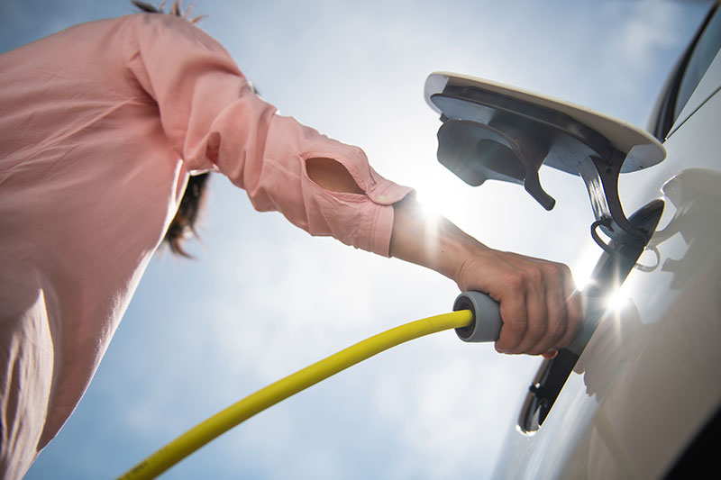 woman plugging in her electric vehicle to charge